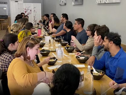 A group enjoying ramen at a long table during a Story of Ramen cooking class, a delicious team building activity in San Francisco.