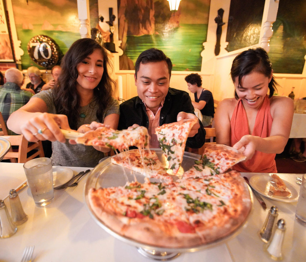 People enjoying stretchy mozzarella pizza during a Stretchy Pants food tour, one of the top team building activities in San Francisco for food lovers.