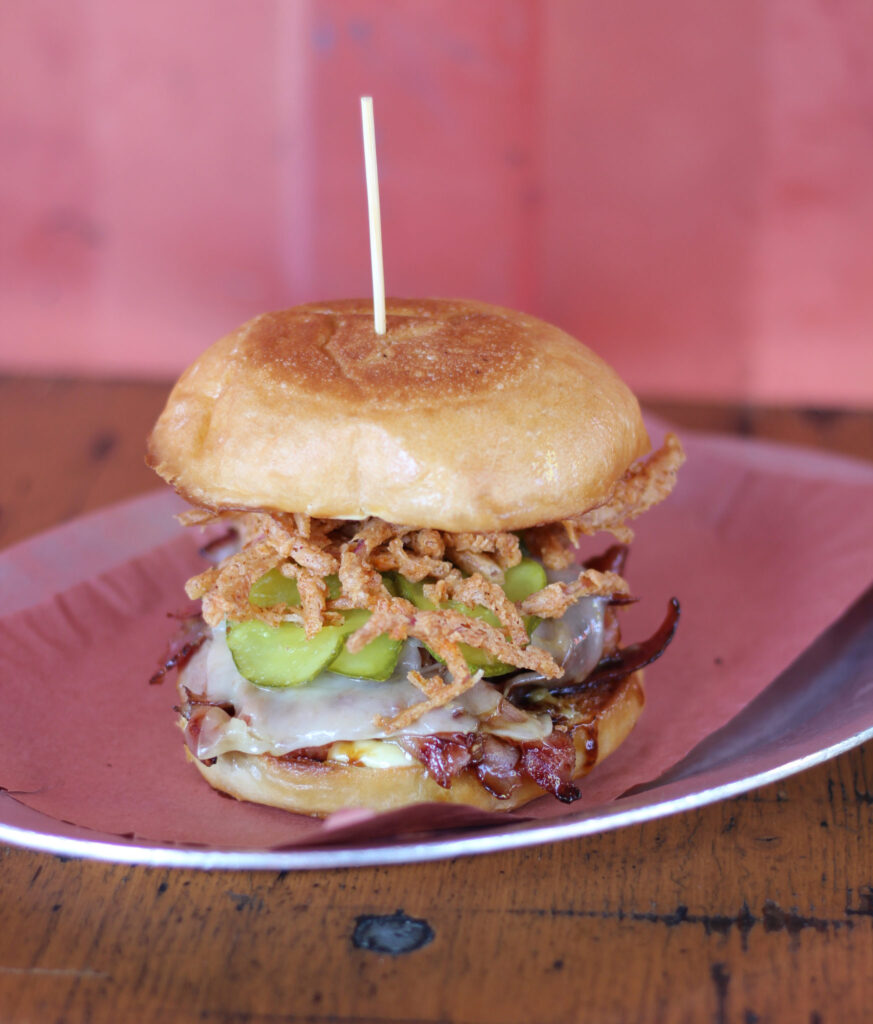 The Easter Ham Sandwich from 4505 Burgers and BBQ, featuring house-cured smoked ham, Gruyère, crispy onion strings, and Acme pain de mie roll.