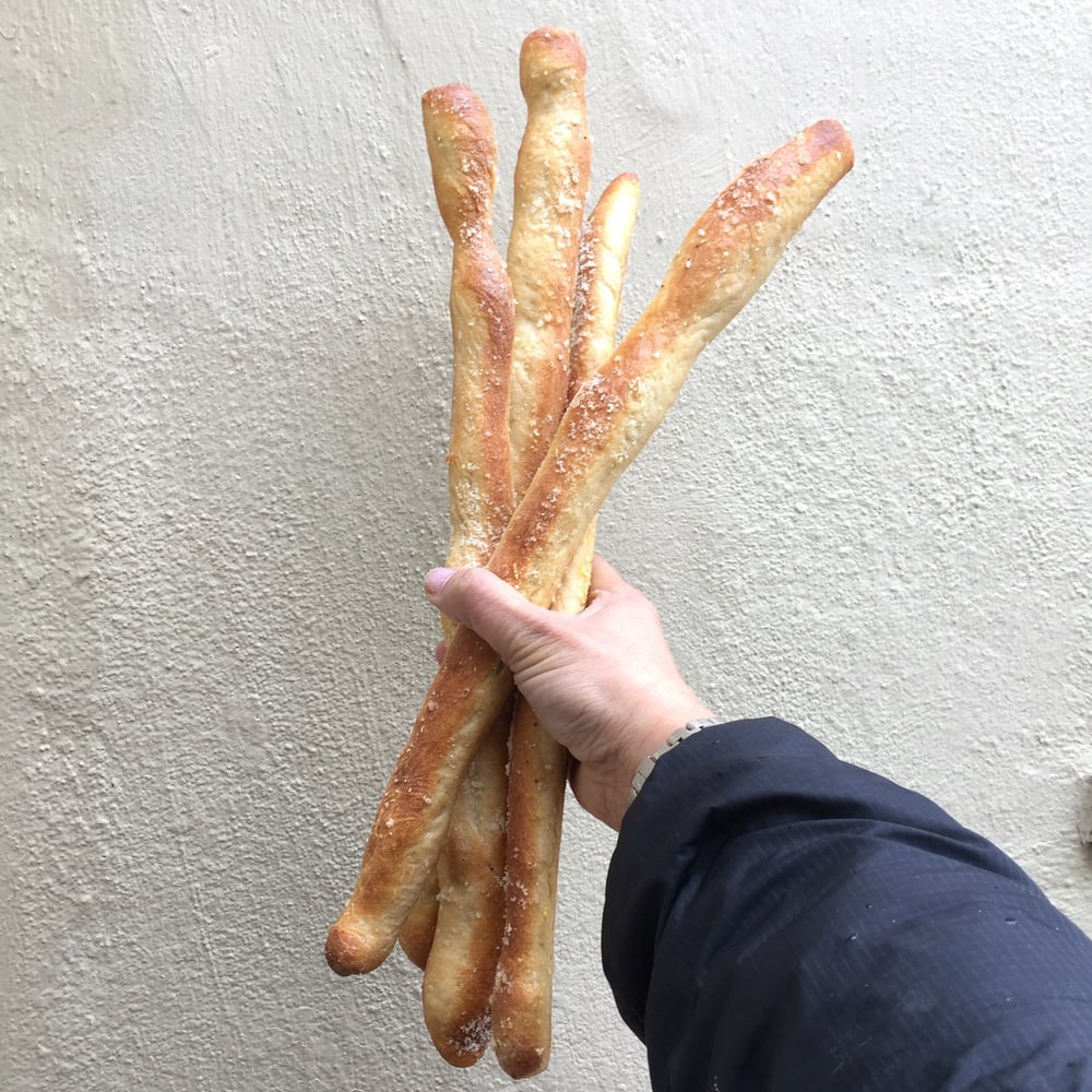 Handful of freshly baked San Francisco sourdough baguettes from Arizmendi Bakery, a worker-owned cooperative known for its artisanal breads and sourdough creations.