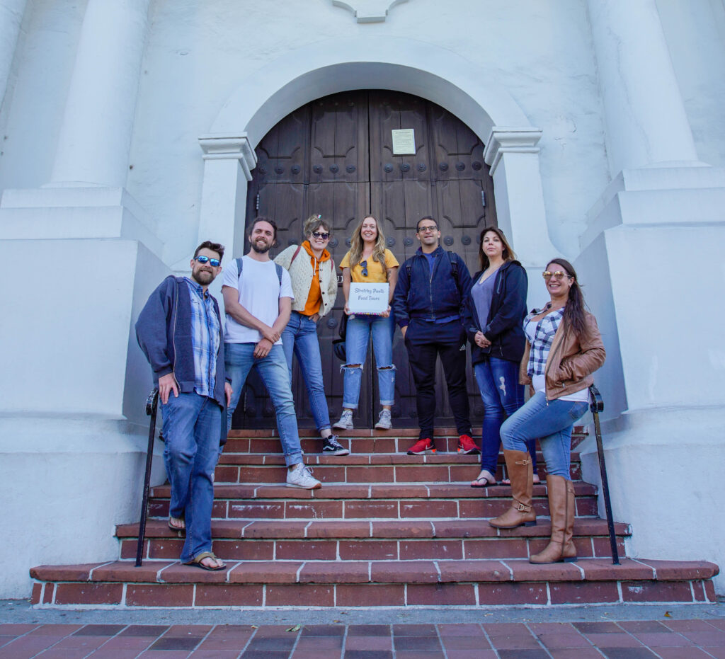 Group of people posing on the steps of an historic building after taking a food tour in San Francisco. 