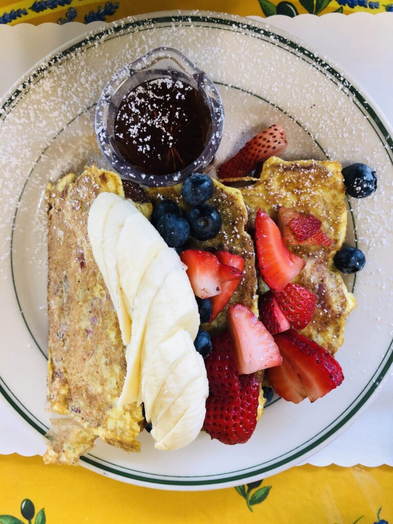 Fluffy buttermilk pancakes topped with fresh fruit and maple syrup served at Mama’s, a cozy San Francisco brunch staple near Washington Square Park.