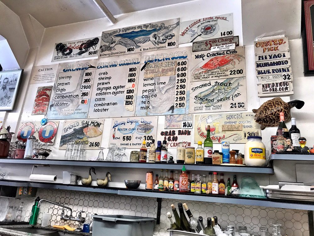 Behind-the-counter view at Swan Oyster Depot, showcasing the bustling atmosphere of this iconic seafood spot known for pairing dishes with classic sourdough bread.